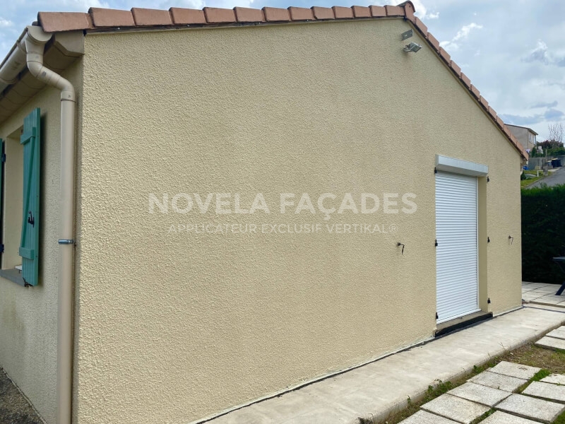 Façade de maison beige avec volets bleus et porte roulante.