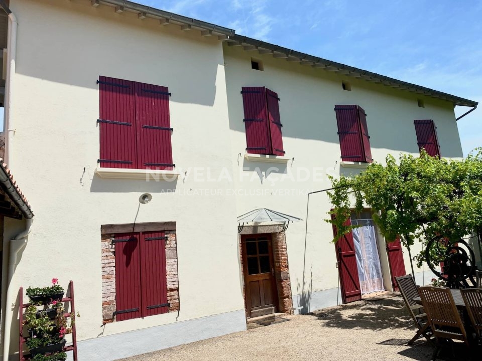 Façades blanches avec volets rouges.