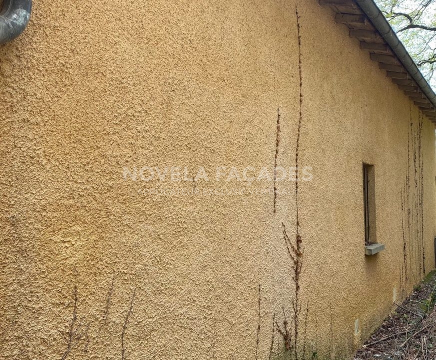 Mur extérieur en stuc jaune avec fissures visibles