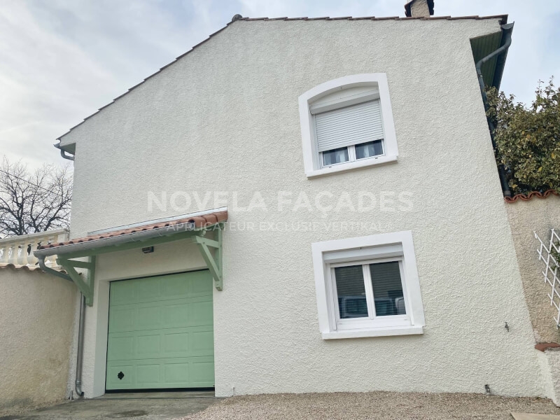Maison blanche avec porte de garage verte et fenêtres.